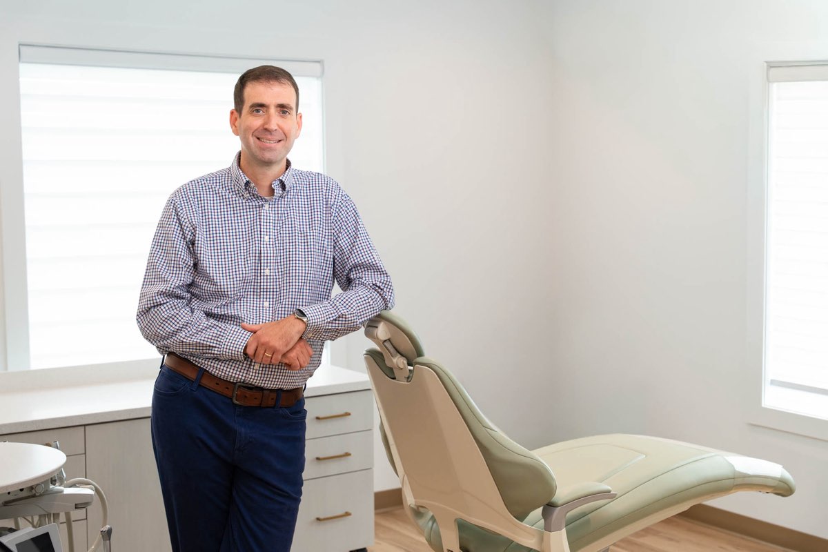 Dr. Ben McDonald leaning on a dental chair in a treatment room