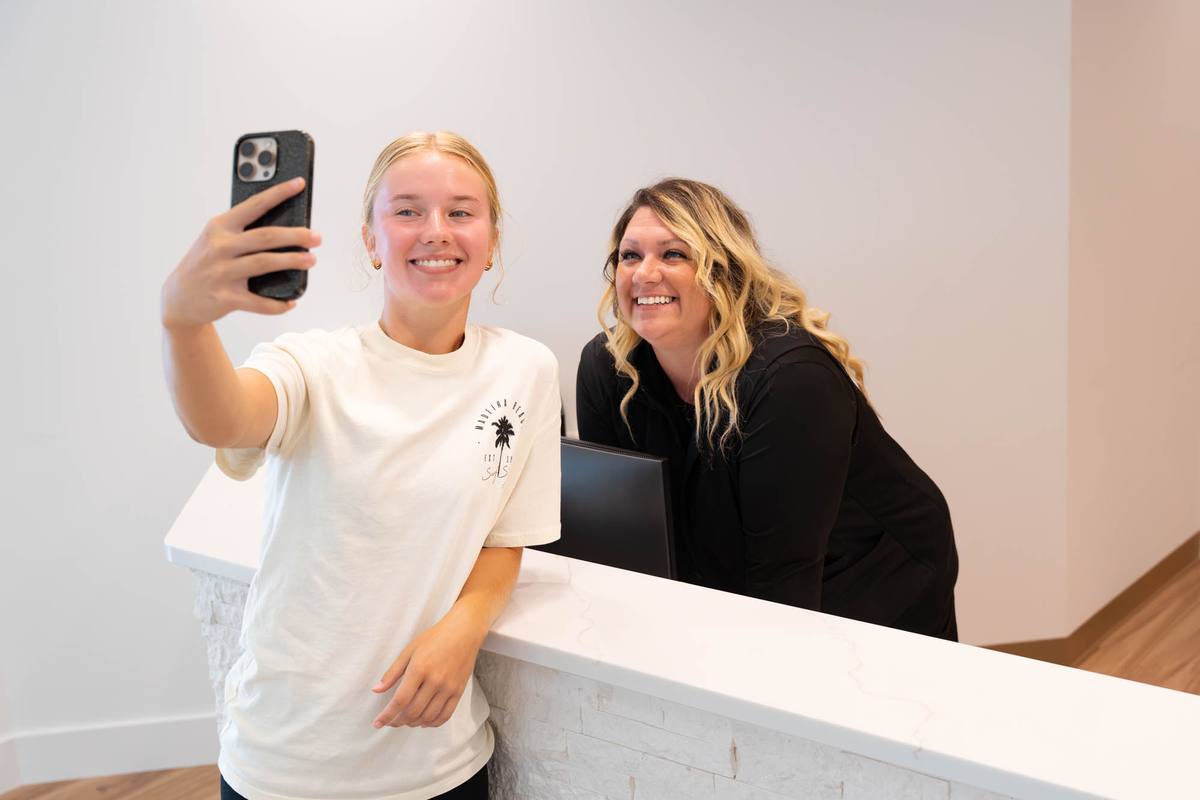 Patient taking a selfie with a smiling team member at the front desk