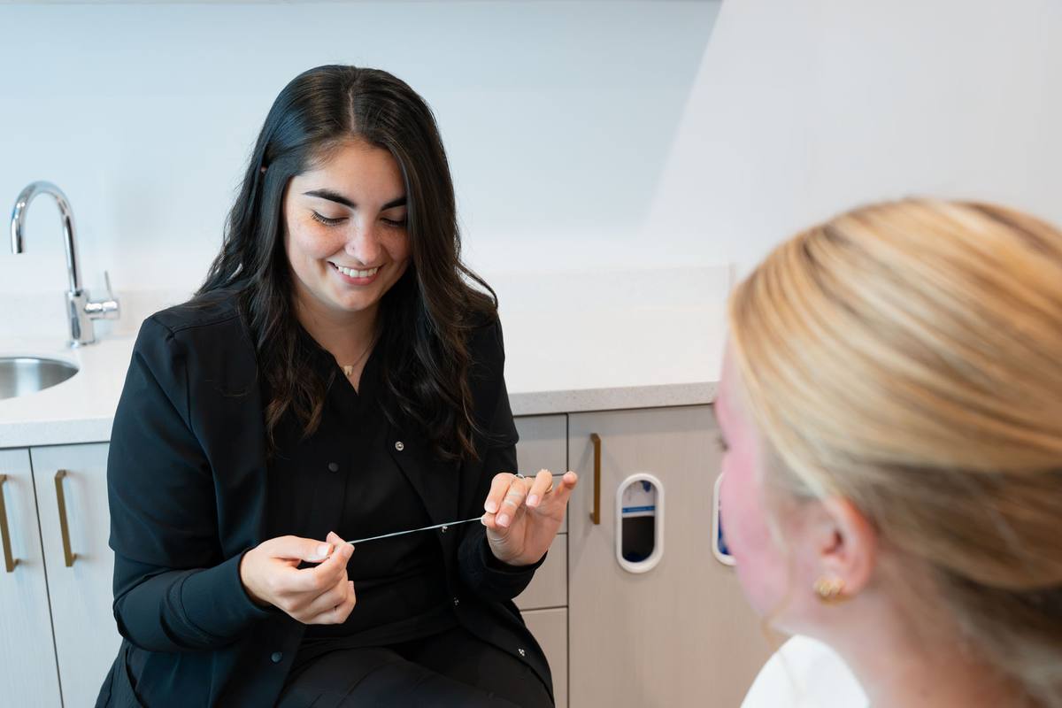 Team member demonstrating flossing to a patient in the treatment chair