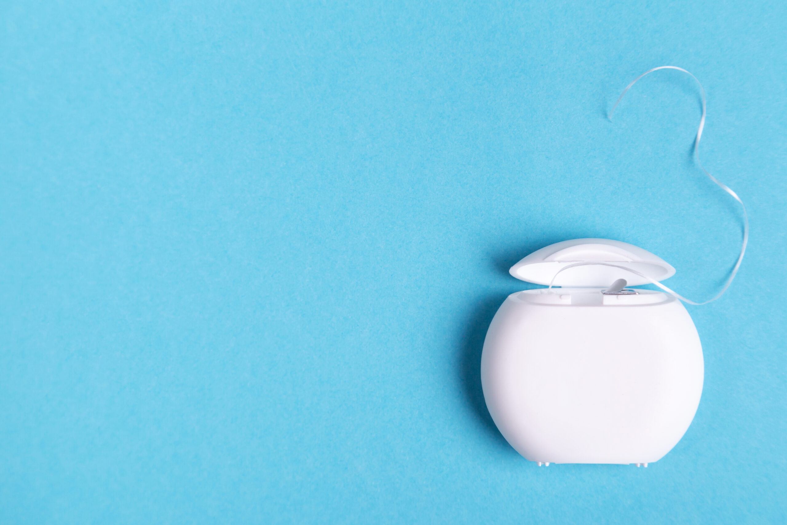 A container of dental floss on a blue background