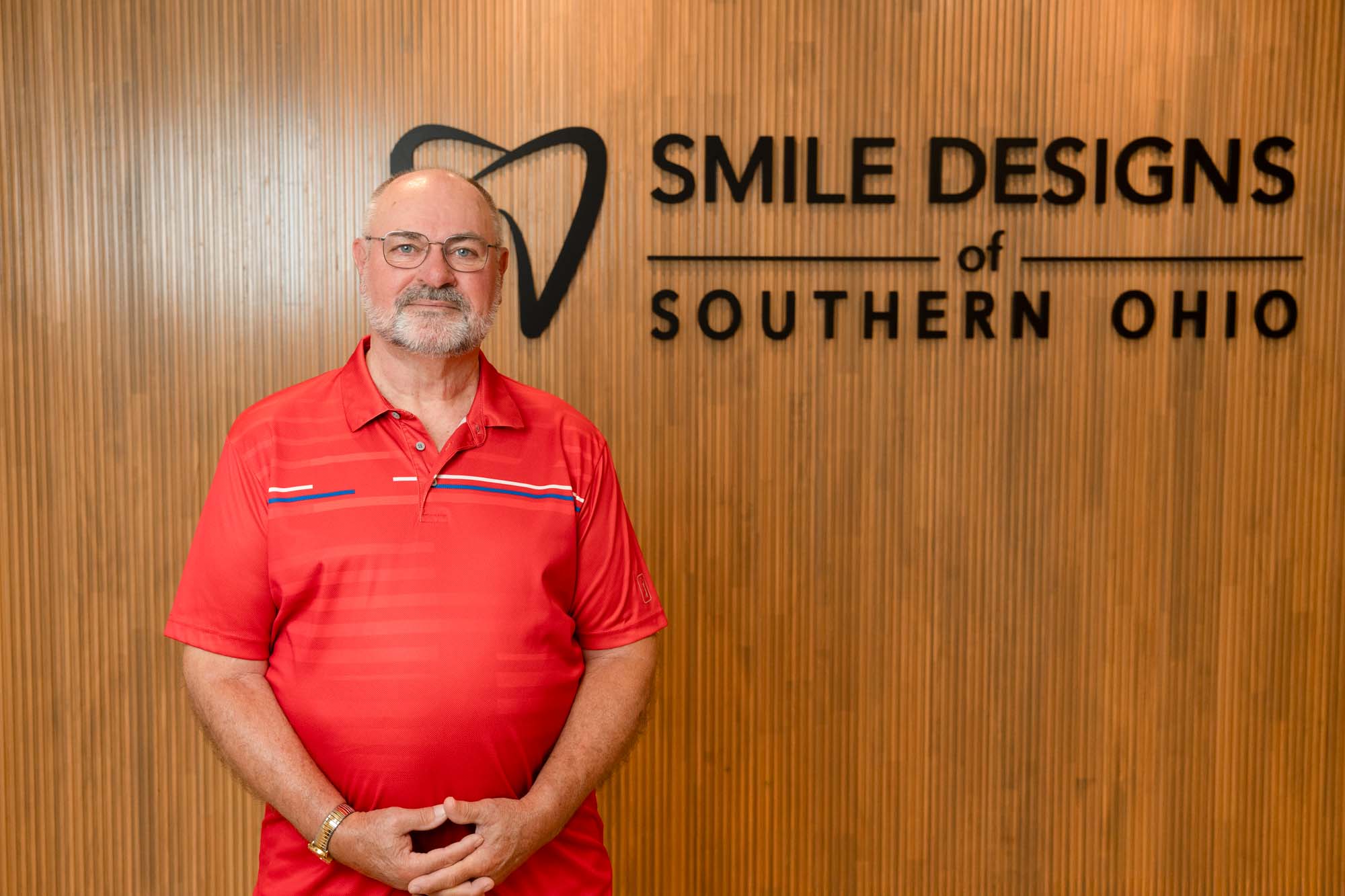Smiling patient standing in front of the Smile Designs of Southern Ohio sign