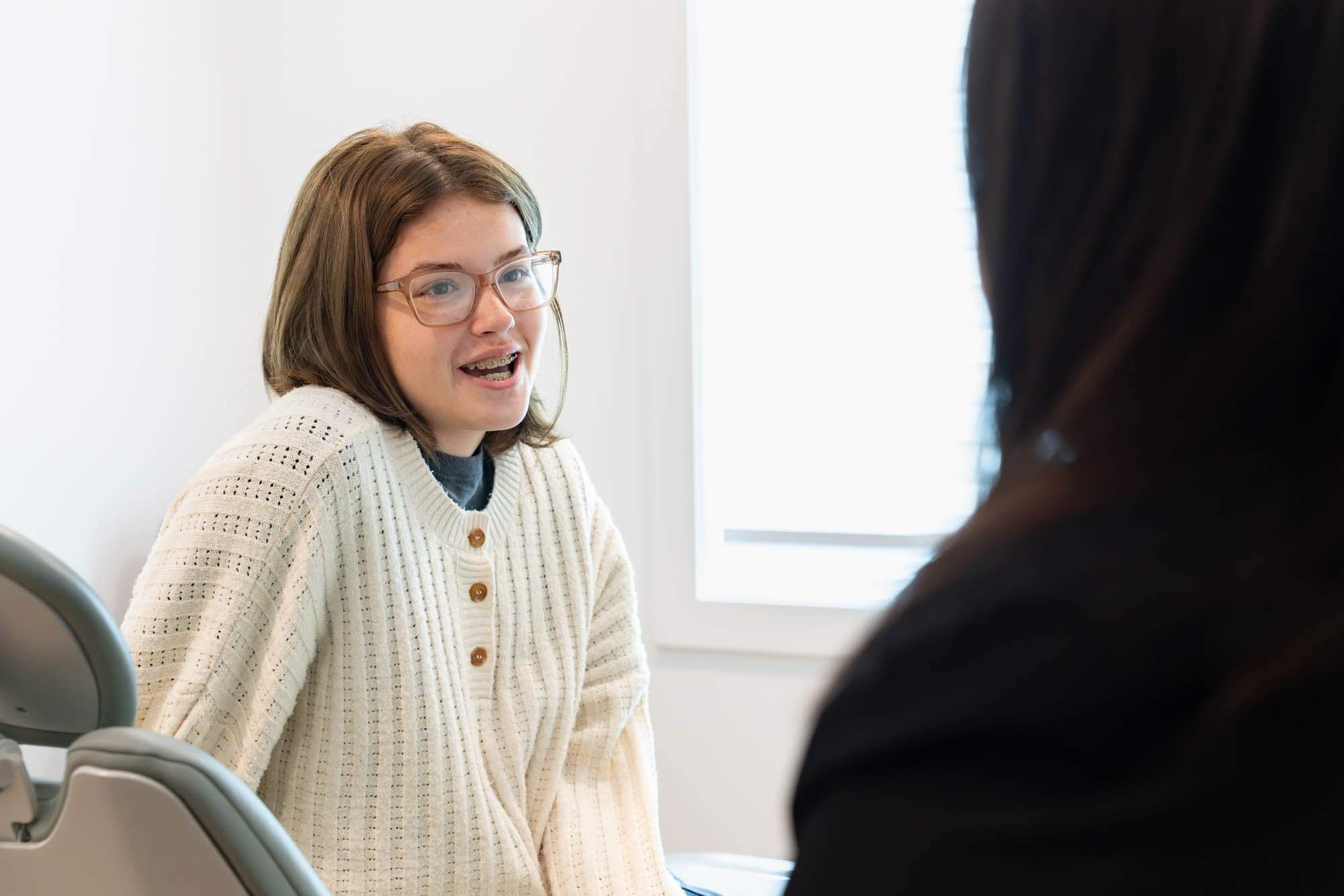 Teen patient in glasses talking with a team member