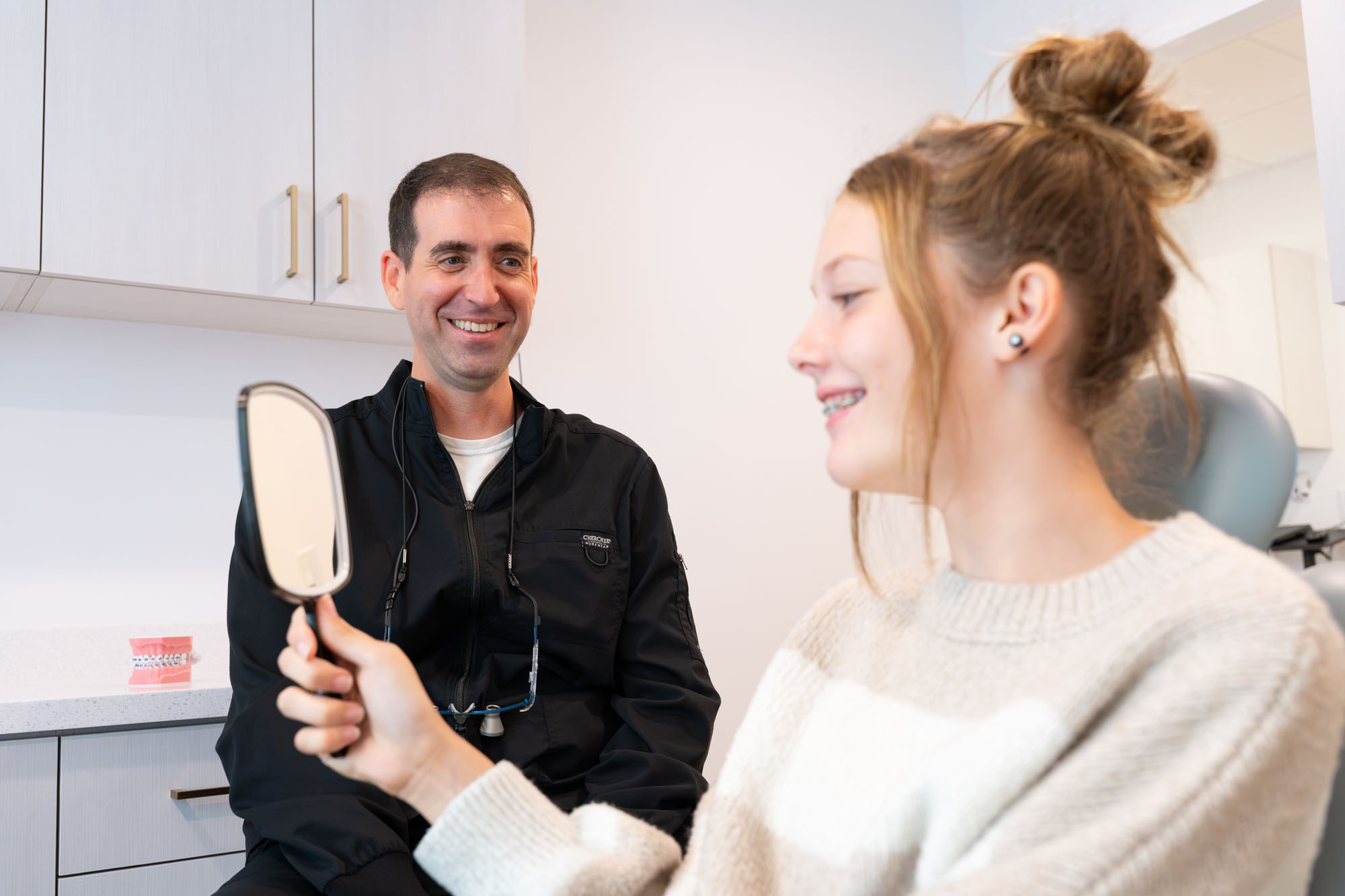 Teen patient with braces looking in a hand mirror