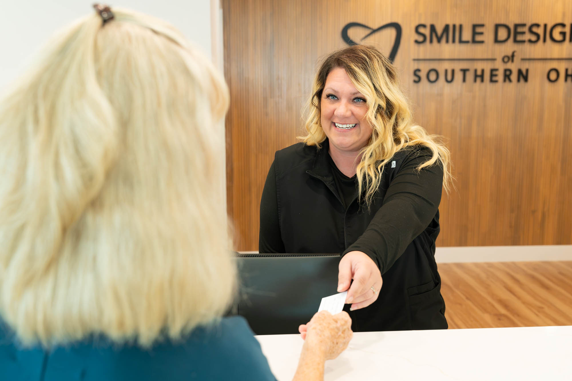 Front desk team member handing a card to a patient