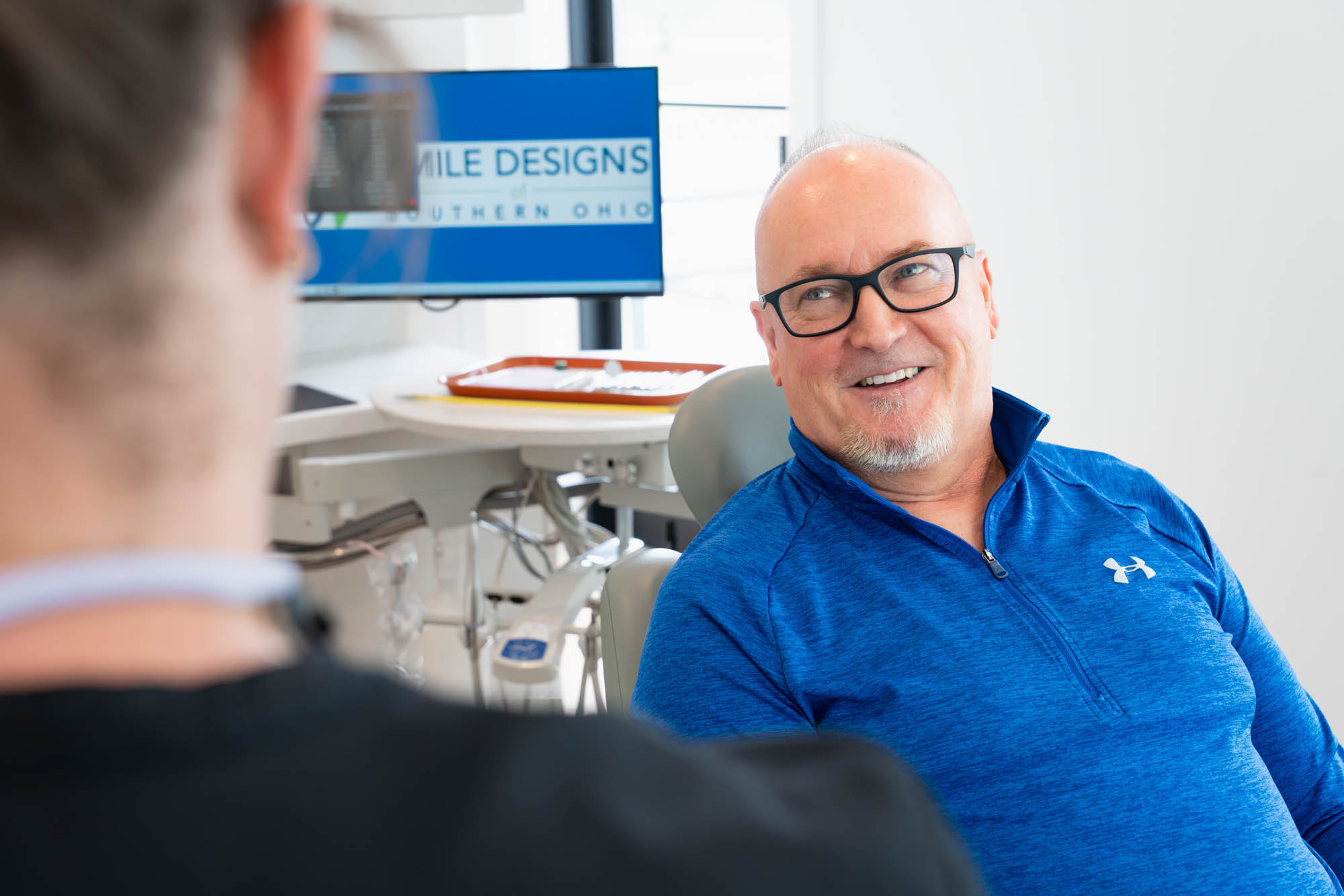 Smiling patient in glasses seated in the treatment chair
