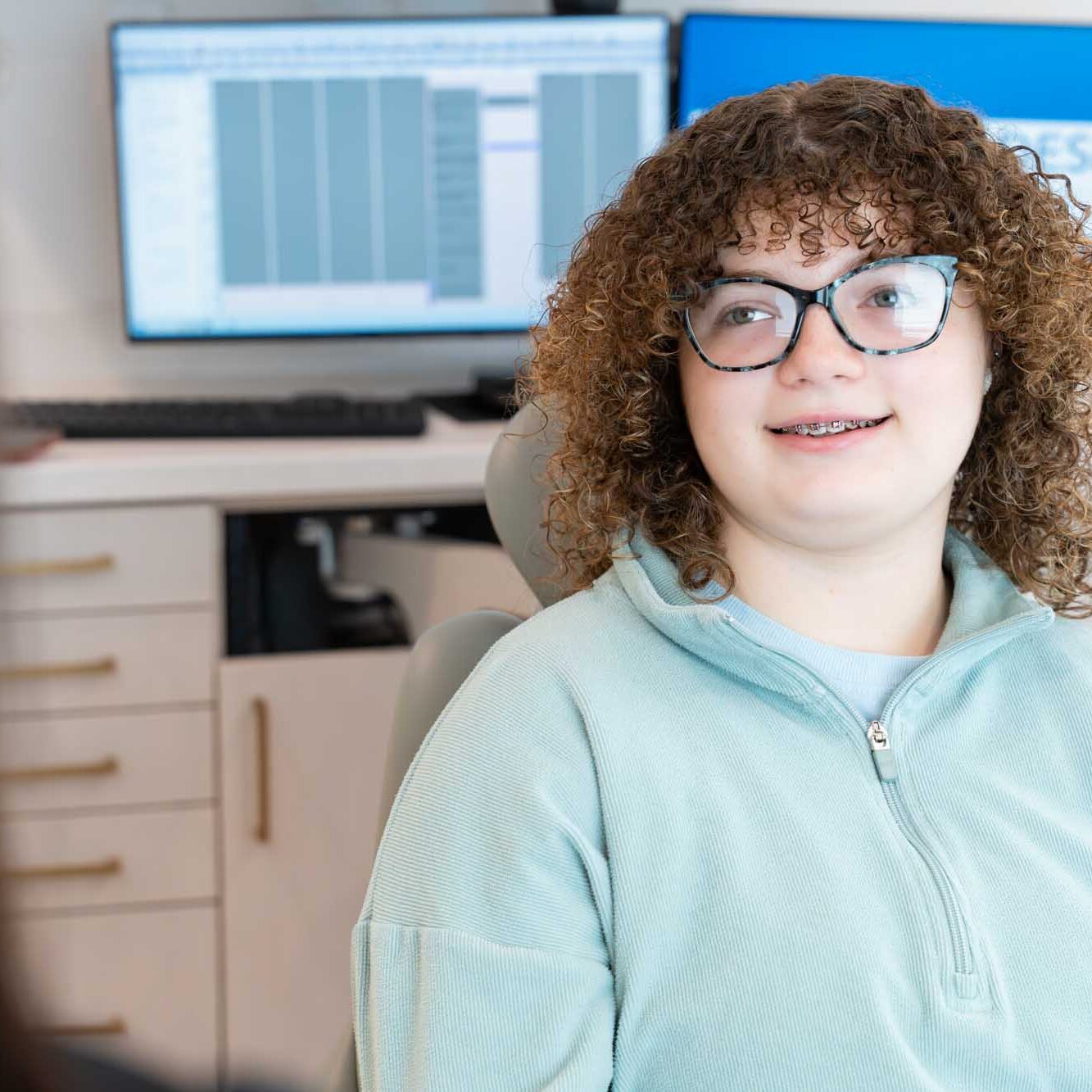 Smiling young patient with curly hair and glasses