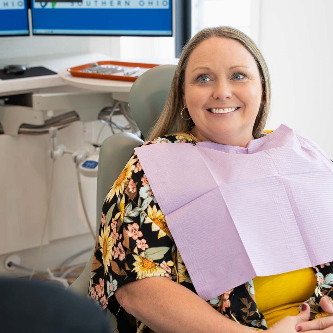 Smiling patient in the treatment chair with a patient bib